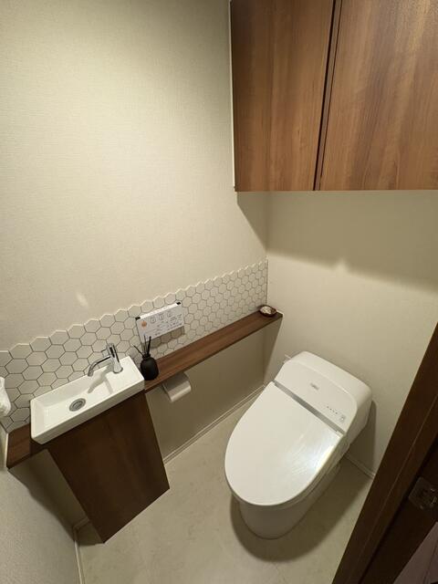 トイレ／手洗いカウンターを設けた、清潔感のあるトイレ空間。吊戸棚など