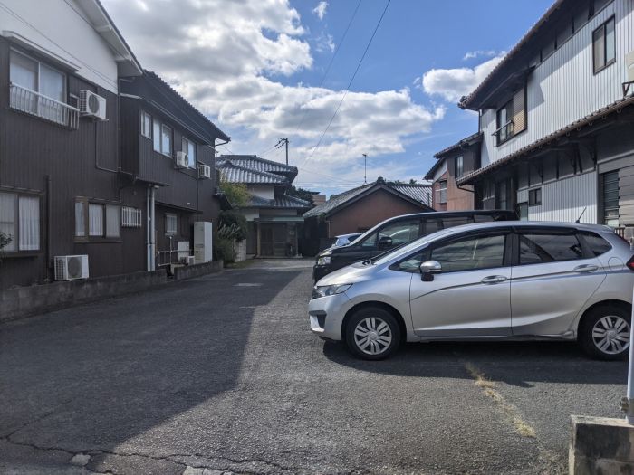 手前：月極駐車場　奥：本件建物