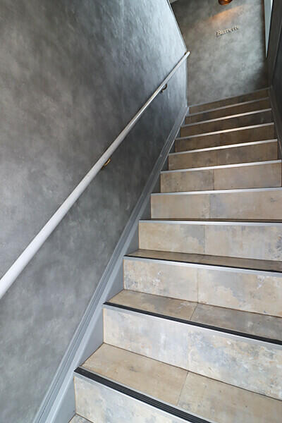 【階段】２階店舗へとつながる階段。グレーの塗り壁風クロスと手