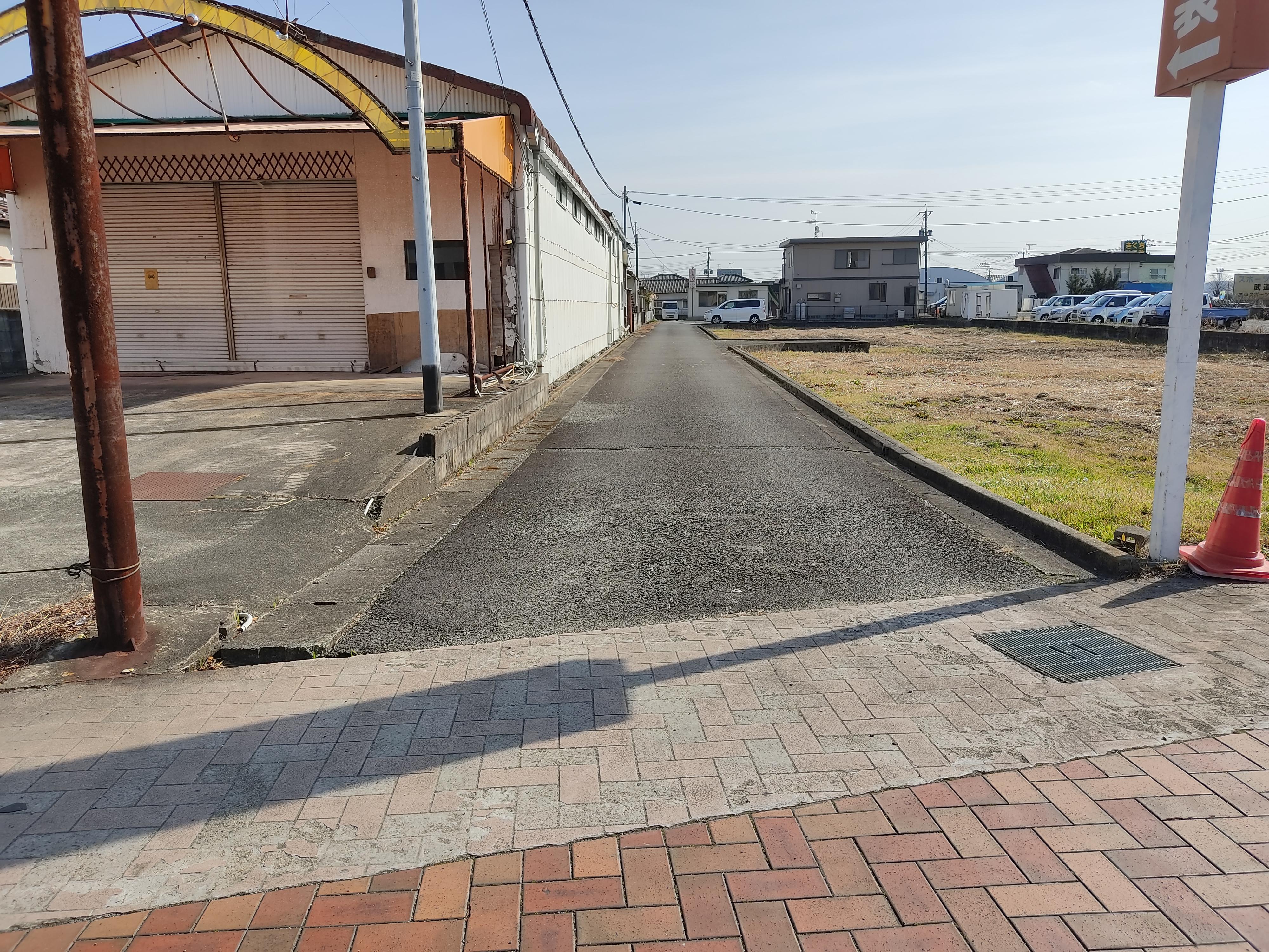 現地土地（前面道路含む）／近隣国道の歩道より接続道路、当物件を遠景で撮影